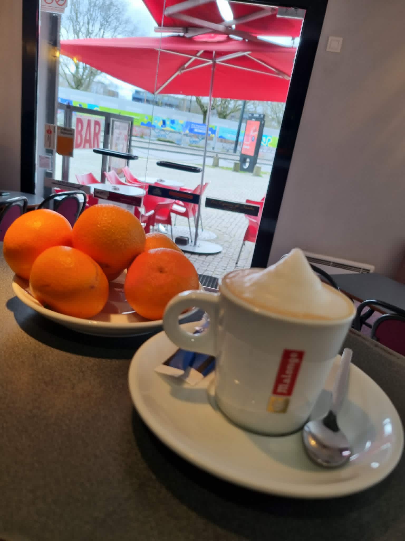 Ambiance chaleureuse du bar avec café fumant et oranges fraîches sur le comptoir
